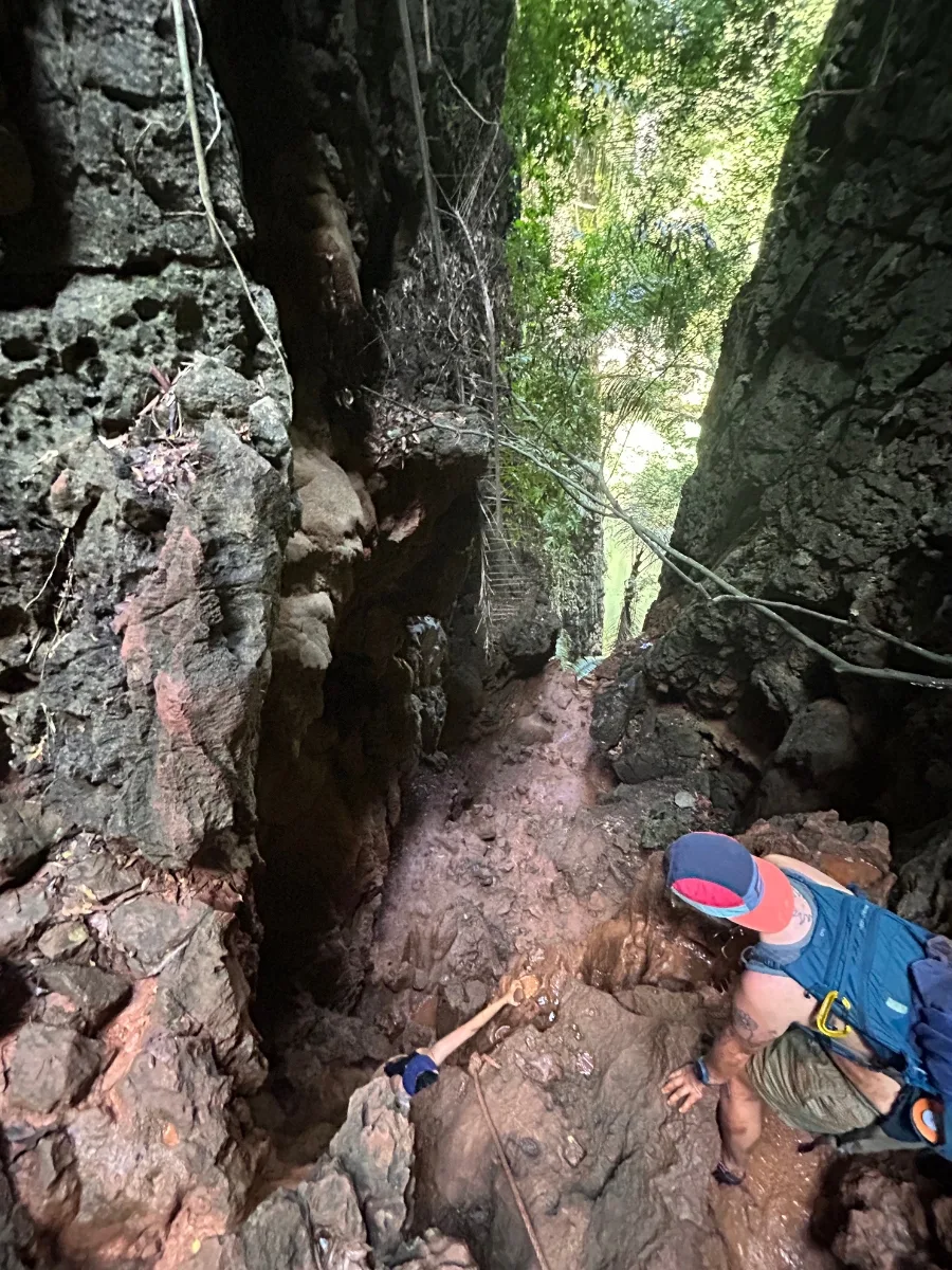 A person looking over a sharp cliff helping another person climb up