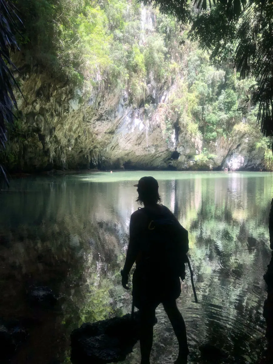 The silhouette of a person standing in front of Railay Beach Lagoon a big green body of water